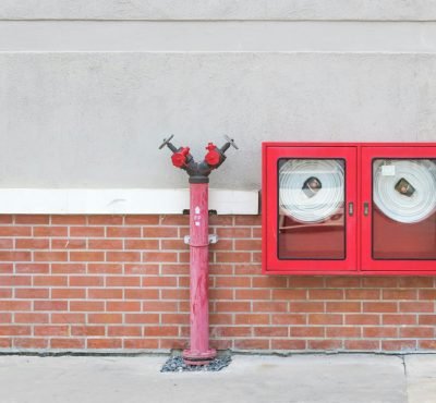 Outdoor fire hydrant and hoses against a brick wall, emphasizing fire safety.